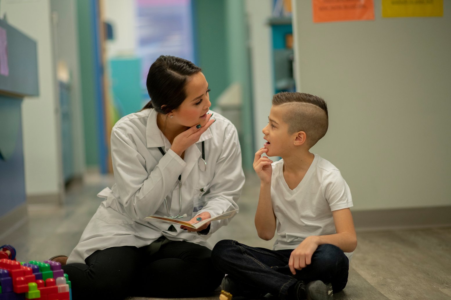 Speech therapist sitting with a child on floor during a verbal exercise